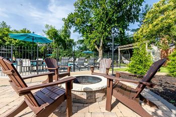 a patio with chairs and a fire pit and umbrellas